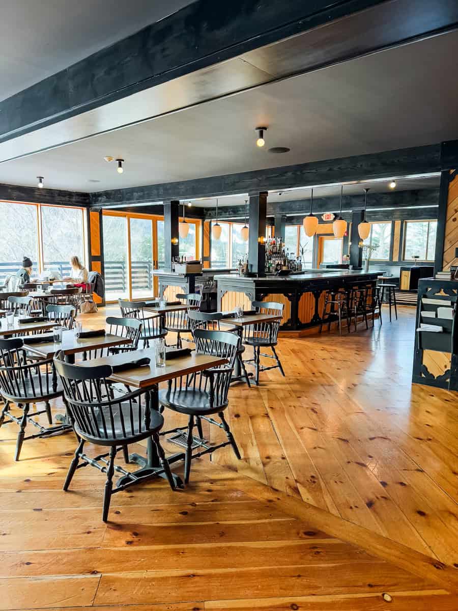 a just-opened restaurant with beautiful wood floors, contrasting chairs and bar, and walls filled with windows and doors to a deck area