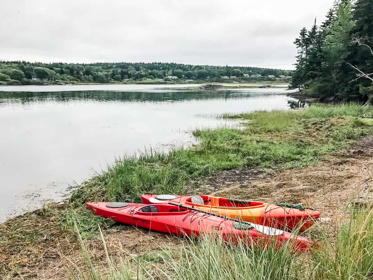 two empty kayaks resting on shore of a lake on a cloudy day as a non-golf activity for any golf getaway
